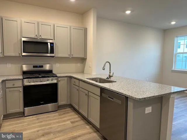 a kitchen with stainless steel appliances granite countertop a sink dishwasher a stove and a microwave oven with white cabinets