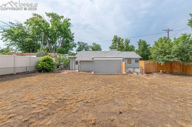 a view of a house with a yard and a large tree
