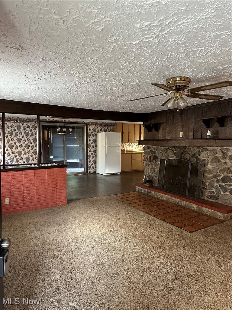 44952 Moose Ridge Road Woodsfield, OH 43793 - Photo 15 of 48 Living room with a stone fireplace, a ceiling fan, carpet, and a textured ceiling