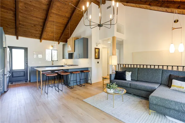 a living room with stainless steel appliances kitchen island granite countertop a table chairs and a wooden cabinets