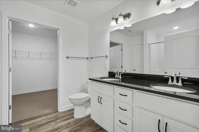 a bathroom with a granite countertop sink a toilet and a mirror
