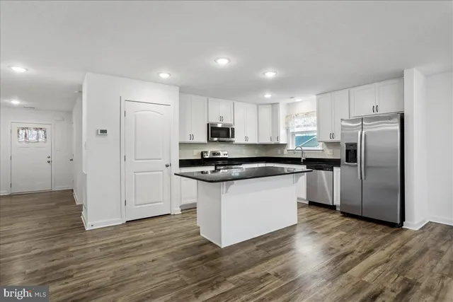 a kitchen with granite countertop a refrigerator and a stove top oven