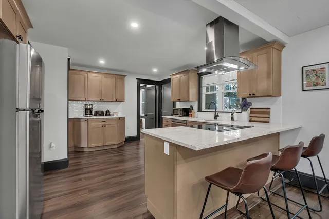 a kitchen with stainless steel appliances kitchen island granite countertop a sink refrigerator and cabinets