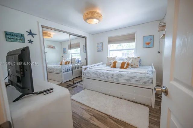 a bedroom with bed and a large mirror next to a window
