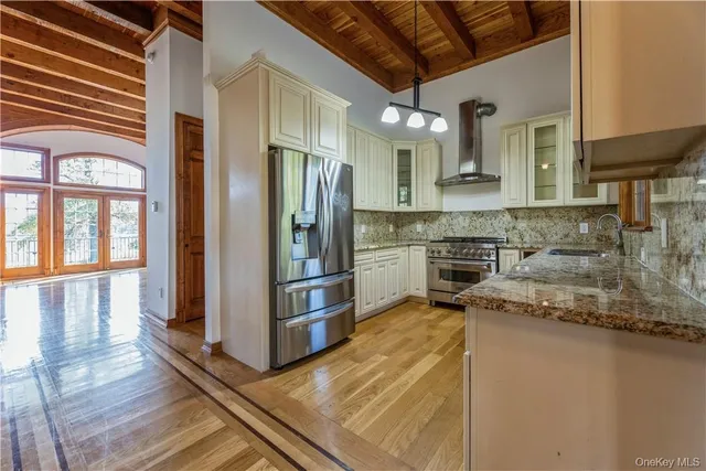 a kitchen with stainless steel appliances granite countertop a refrigerator a stove and a sink with wooden floor