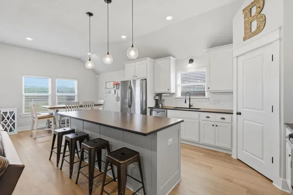 an open kitchen with granite countertop a stove a sink a center island cabinets and wooden floor