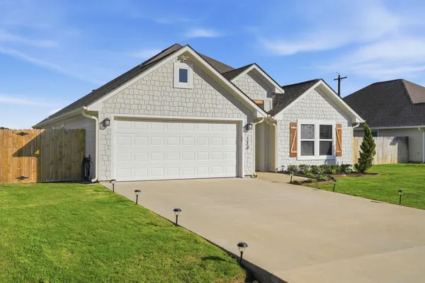 a front view of a house with a garden and yard