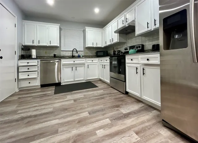 a kitchen with white cabinets stainless steel appliances and sink