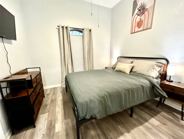 a bedroom with a bed and a flat tv screen on a dresser