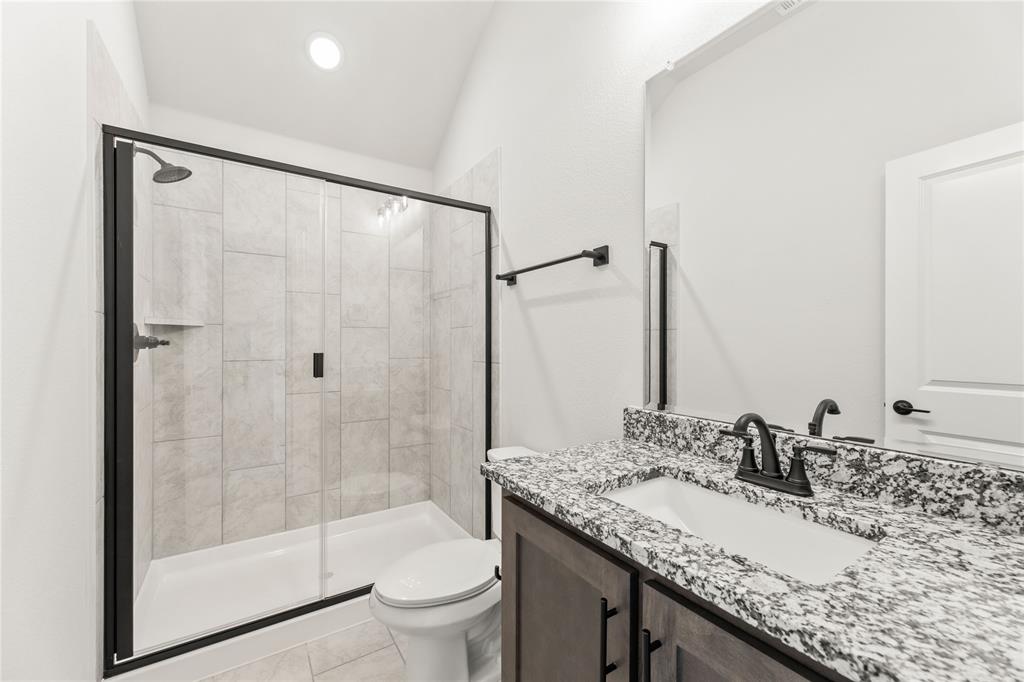 4213 Bel Air Drive Midlothian, TX 76065 - Photo 33 of 40 a bathroom with a granite countertop sink a toilet and shower