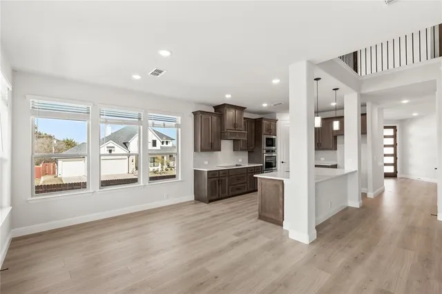 a large living room with stainless steel appliances kitchen island granite countertop a large counter top and a wooden floors