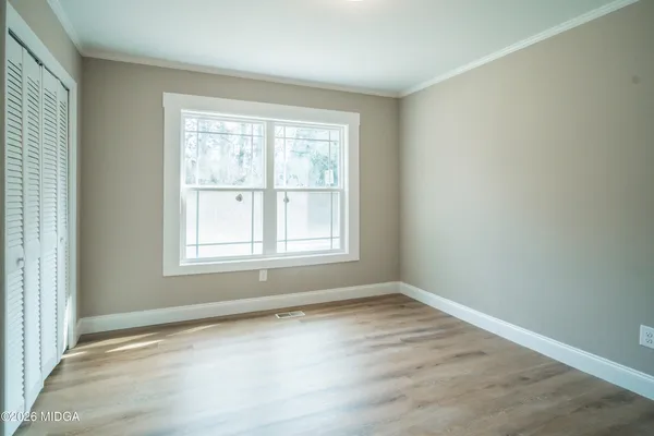 an empty room with wooden floor and windows