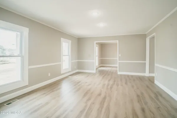 an empty room with wooden floor and windows