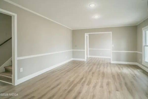 a view of an empty room with wooden floor and closet
