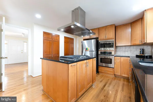 a kitchen with stainless steel appliances a stove a sink dishwasher a refrigerator and a oven with wooden floor