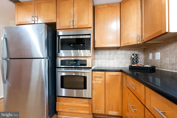 a kitchen with stainless steel appliances granite countertop a refrigerator a stove and a sink with cabinets