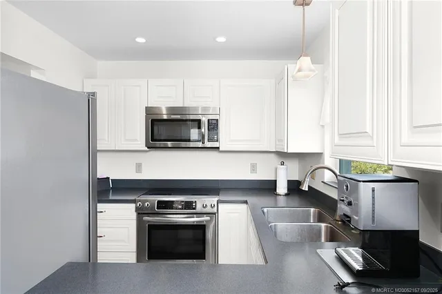 a kitchen with stainless steel appliances a stove a microwave a sink and white cabinets