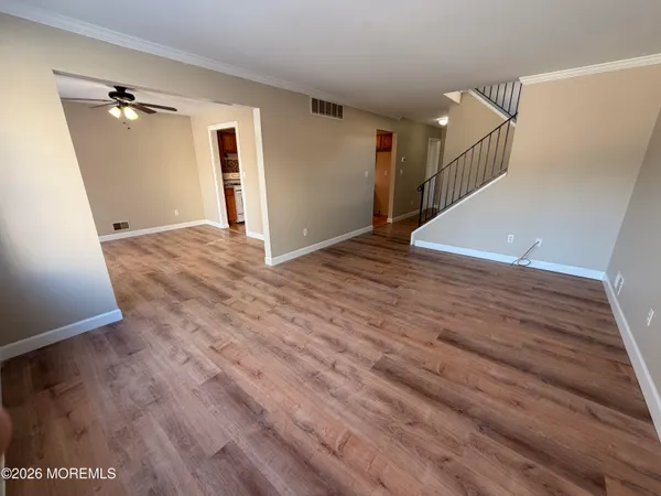 a view of empty room with wooden floor and fan