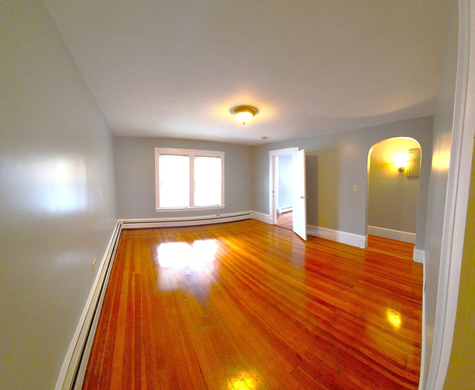 a view of empty room with window and wooden floor