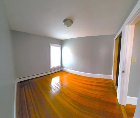 a view of empty room with window and wooden floor