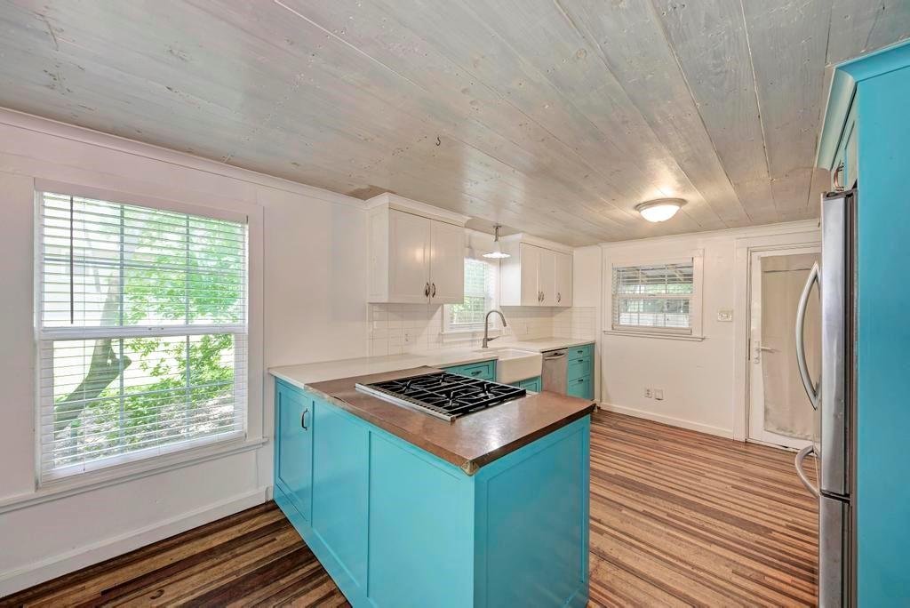 1407 Leona Street, Unit A Austin, TX 78702 - Photo 12 of 25 Kitchen featuring blue cabinetry, dark wood-type flooring, stainless steel appliances, white cabinetry, and wood ceiling
