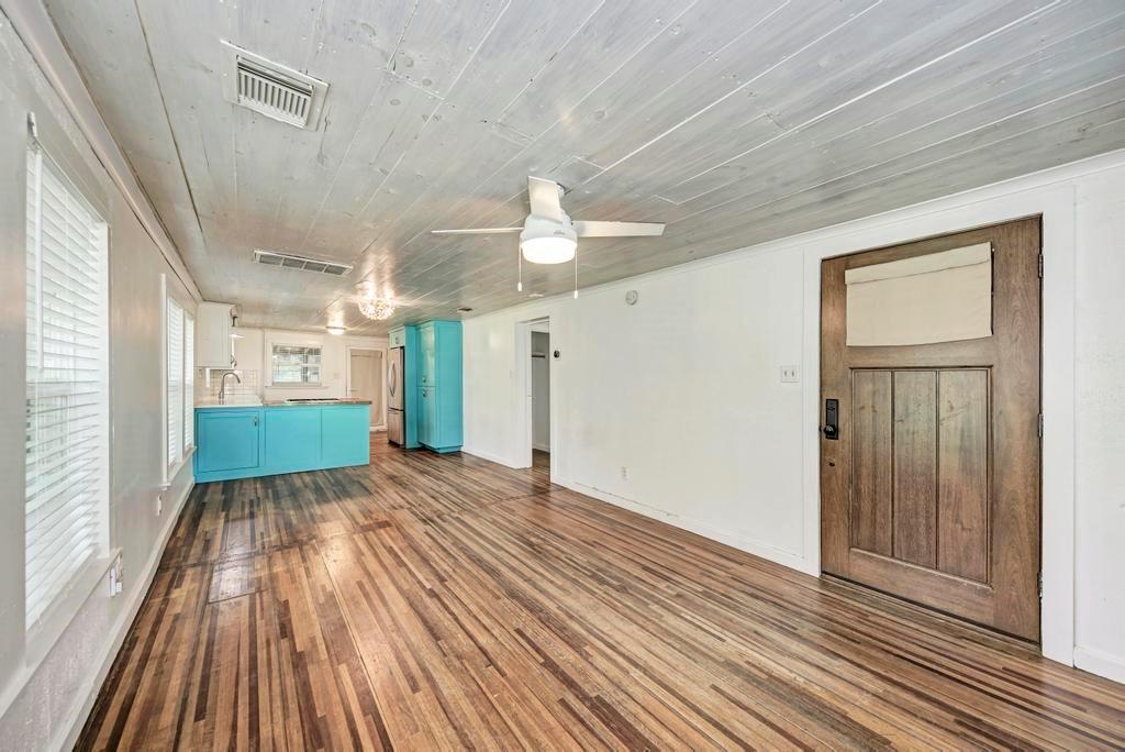 1407 Leona Street, Unit A Austin, TX 78702 - Photo 8 of 25 Unfurnished living room featuring dark wood finished floors, a ceiling fan, and wooden ceiling