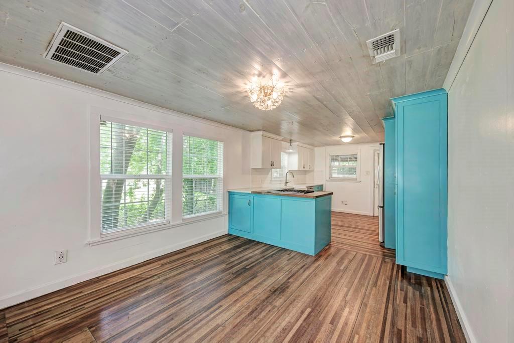 1407 Leona Street, Unit A Austin, TX 78702 - Photo 10 of 25 Kitchen with blue cabinets, a peninsula, dark wood finished floors, pendant lighting, and white cabinetry