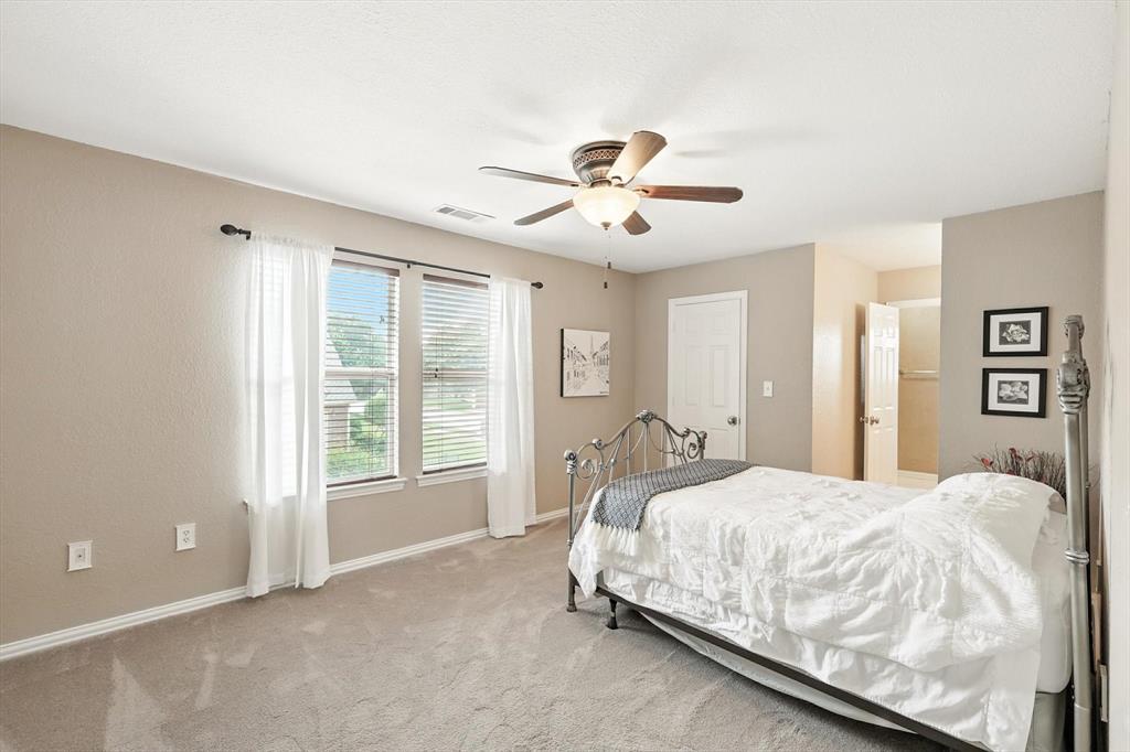 109 Visalia Lane Denton, TX 76210 - Photo 22 of 36 a bedroom with a large bed and a chandelier