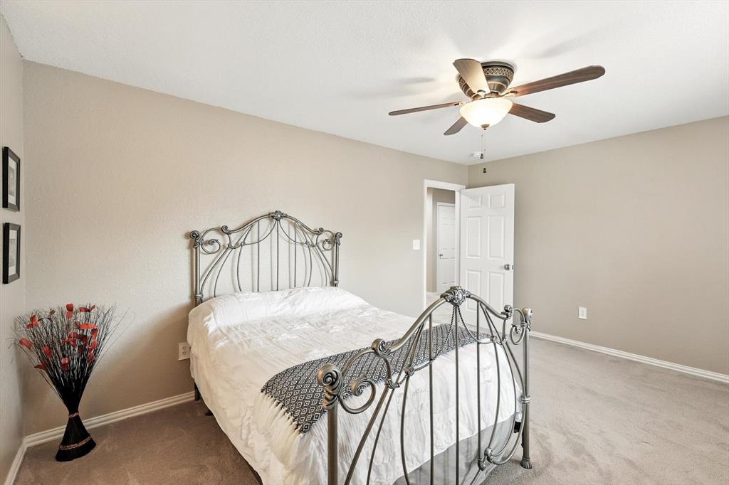 109 Visalia Lane Denton, TX 76210 - Photo 23 of 36 a bedroom with a bed and a chandelier