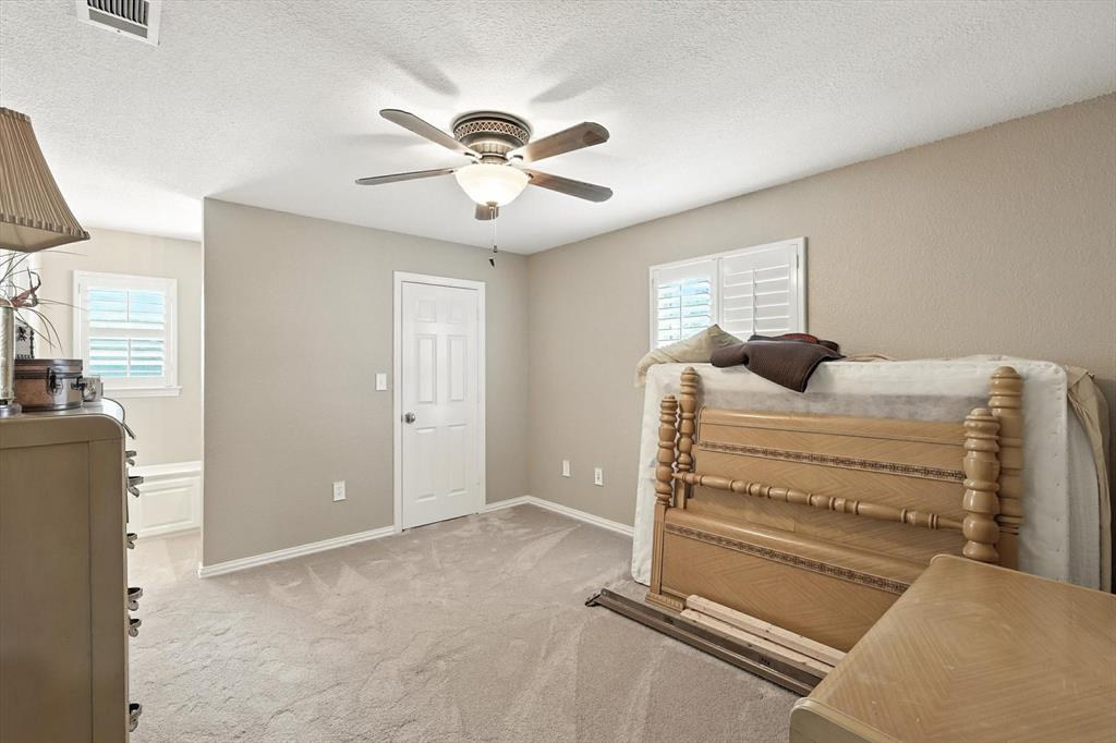 109 Visalia Lane Denton, TX 76210 - Photo 24 of 36 a bedroom with a bed and a chandelier
