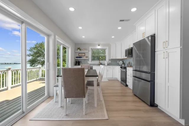 a kitchen with stainless steel appliances granite countertop a refrigerator a stove top oven and a dining table with wooden floor