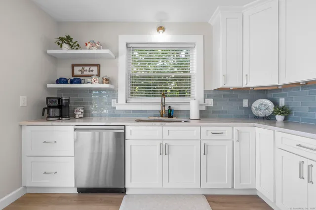 a kitchen with white cabinets and window
