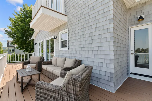 a balcony with couches and a potted plant on a wooden floor