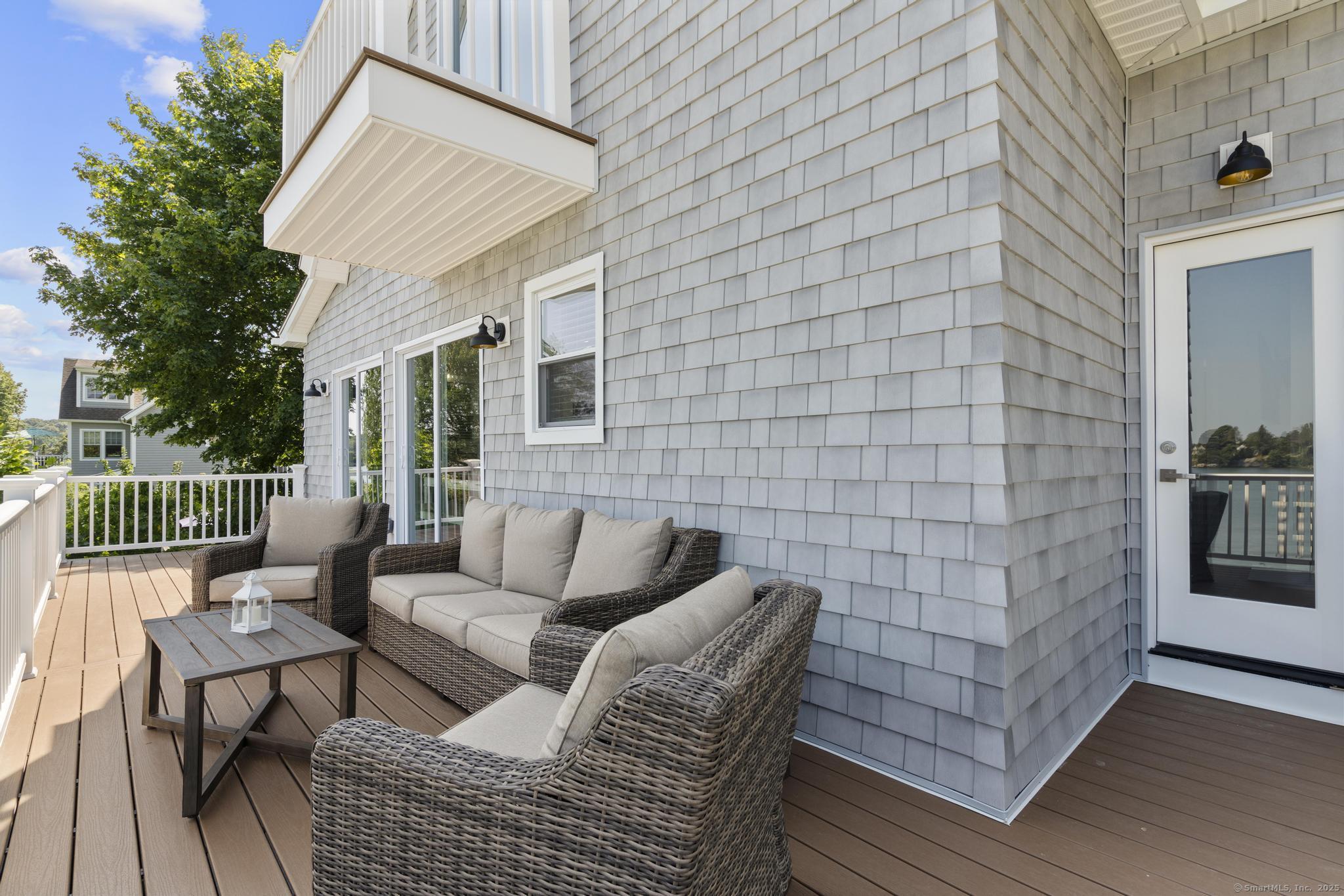 270 Elm Street, Unit 2 Groton, CT 06340 - Photo 22 of 36 a balcony with couches and a potted plant on a wooden floor