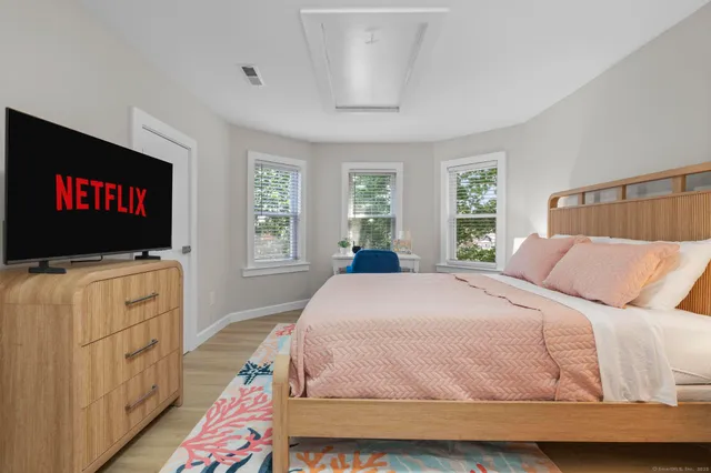 a bed sitting in a bedroom next to a window and a chair