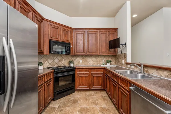 a kitchen with stainless steel appliances granite countertop a sink stove microwave and refrigerator