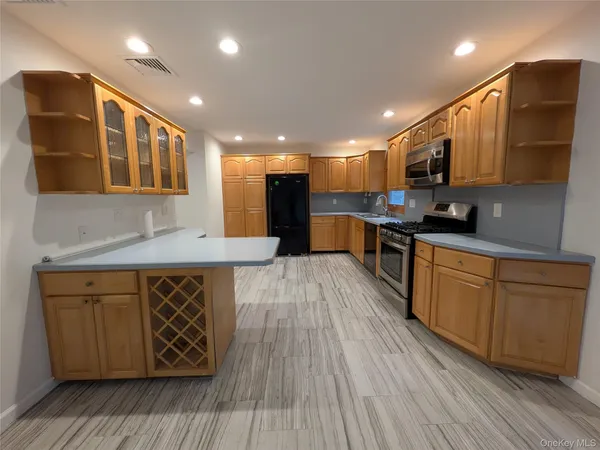 a kitchen with stainless steel appliances granite countertop wooden cabinets a sink dishwasher a stove and a refrigerator with wooden floor