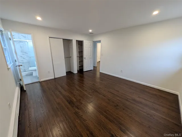 a view of an empty room with wooden floor and closet