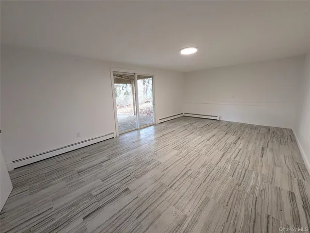 a view of an empty room with wooden floor and cabinet
