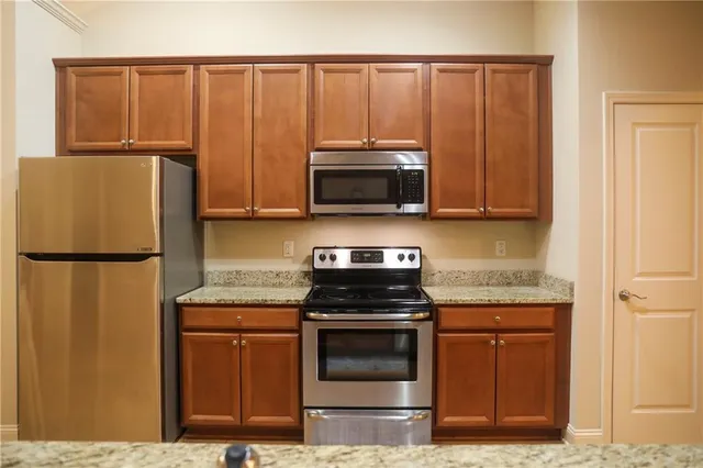 a kitchen with granite countertop a refrigerator stove and microwave
