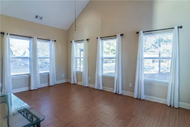 an empty room with wooden floor and windows