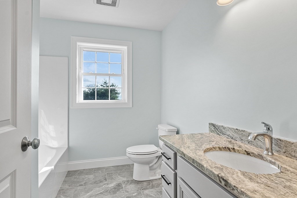 8 Worcester Road, Unit LOT 1 Westminster, MA 01473 - Photo 31 of 38 a bathroom with a granite countertop toilet a sink and a mirror