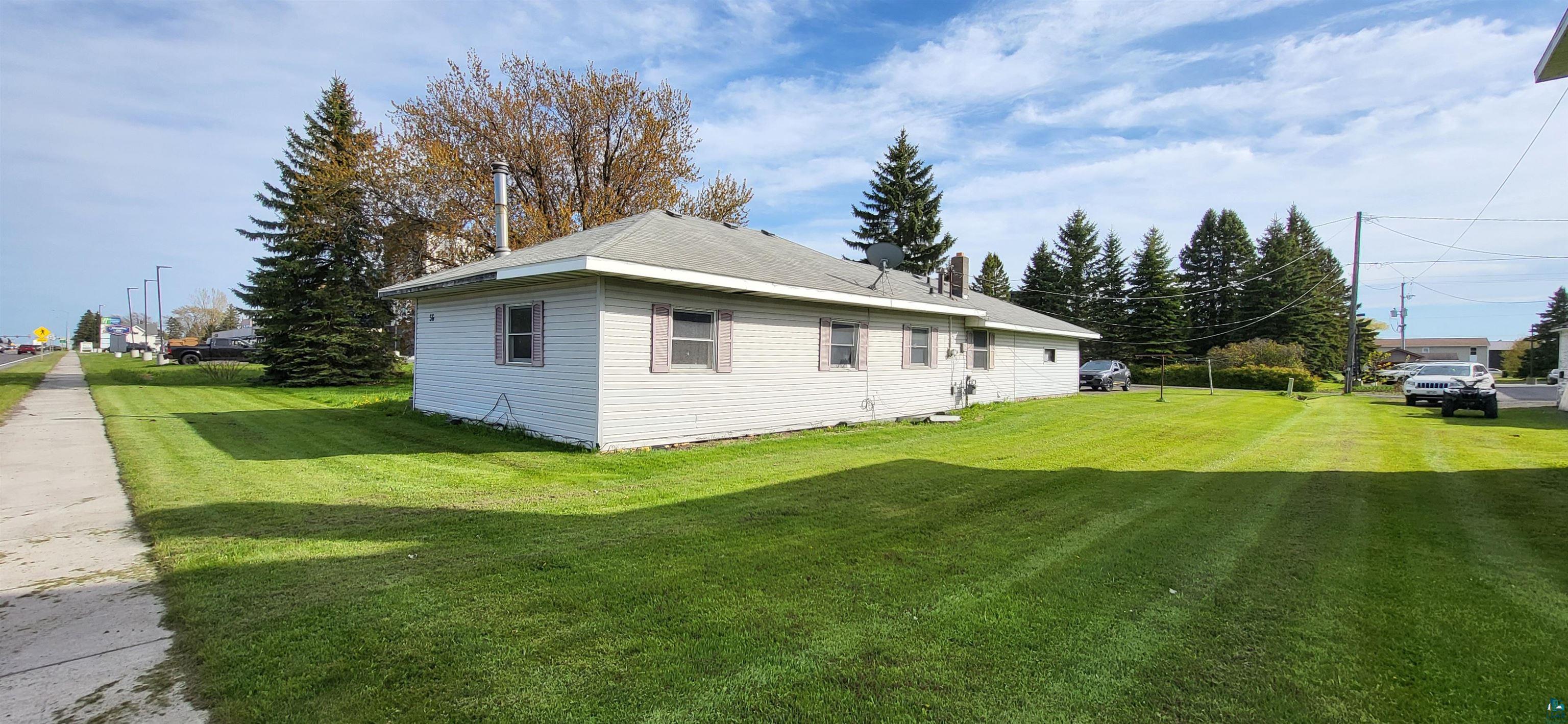 56 East 2nd Street Superior, WI 54880 - Photo 2 of 18 Single-story residence featuring light-colored siding, a dark shingle roof, multiple windows with shutters, and a spacious green lawn