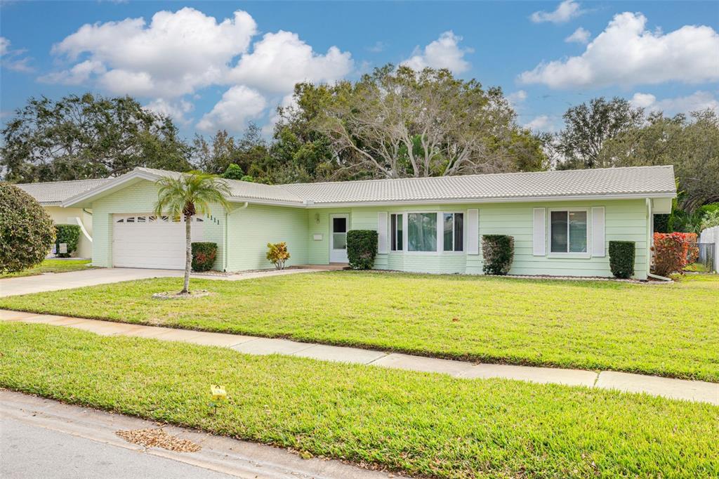 1111 McLean Street Dunedin, FL 34698 - Photo 1 of 1 a front view of a house with a garden
