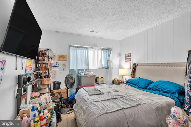 a bedroom with a bed a computer on desk and a window