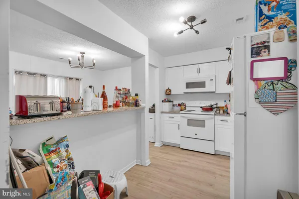 a kitchen with a white stove top oven and white cabinets with wooden floor