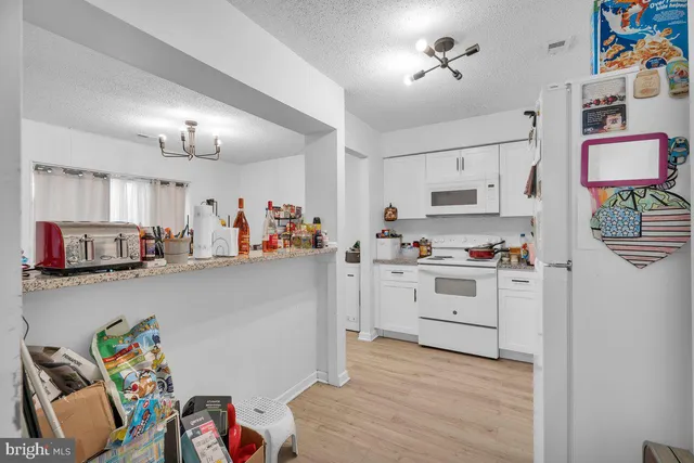 a kitchen with a white stove top oven and white cabinets with wooden floor