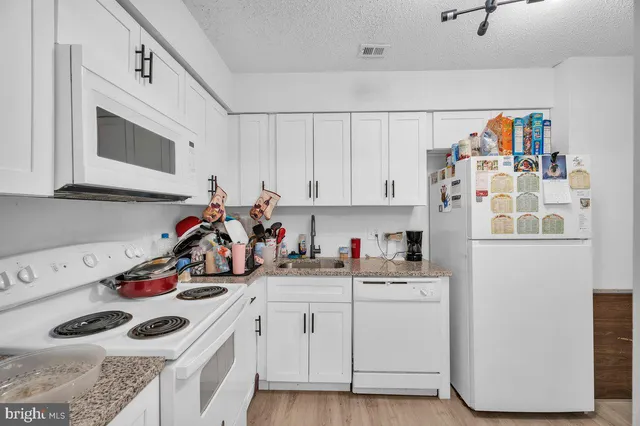 a view of a kitchen with sink and white cabinets