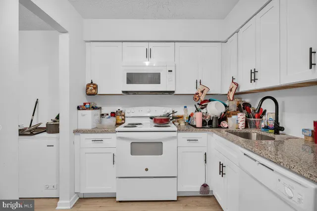 a kitchen with white cabinets and sink