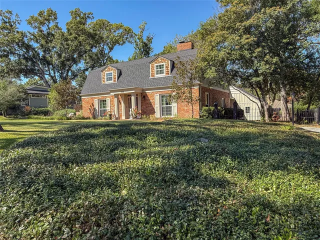 a view of a big house with a big yard and large trees